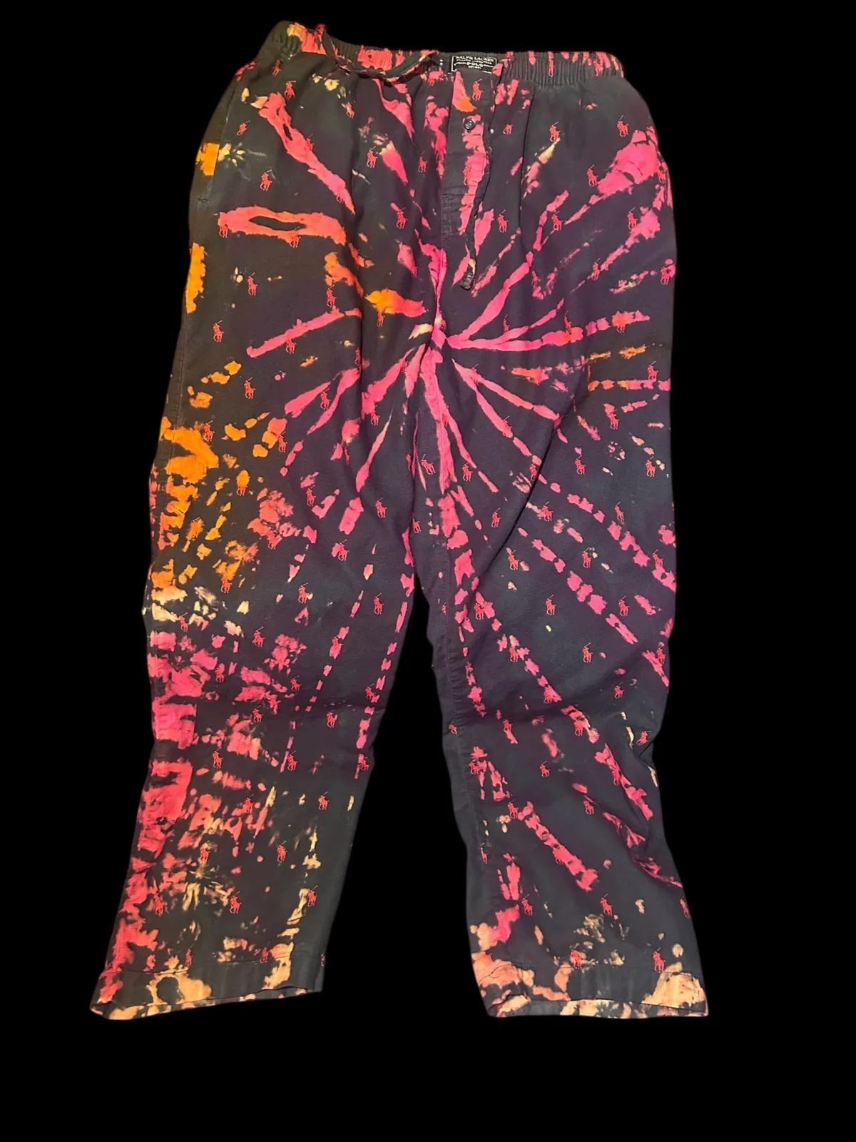 Black hand-dyed pants with a vivid pink and orange spiral pattern